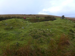 An excavated cairn on the route with a bag for scale 